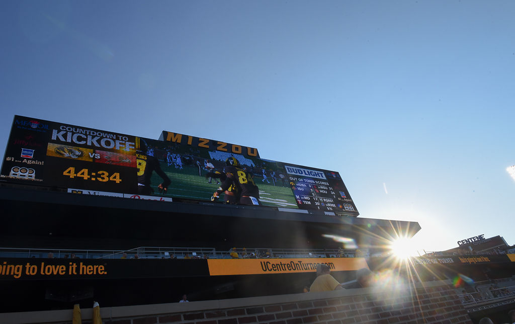 The scoreboard in the south end zone shows players warming up